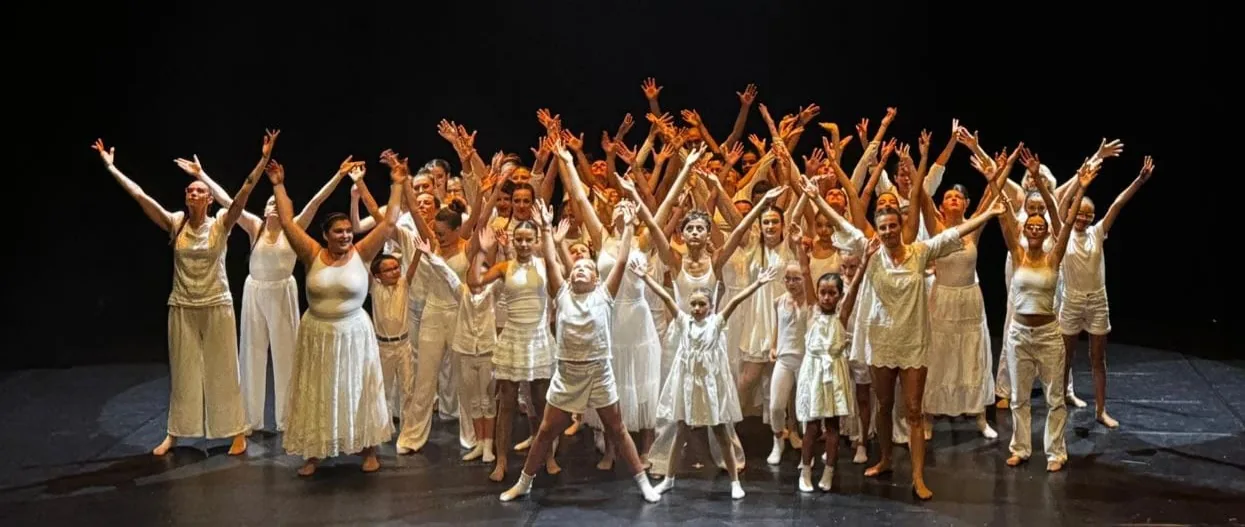 Les élèves de l’école, bras levés sur scène, lors du spectacle de fin d’année